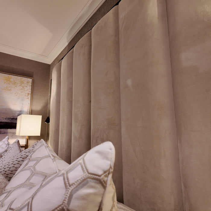 Custom Belle bed with a super-high beige upholstered paneled headboard in a cozy bedroom.