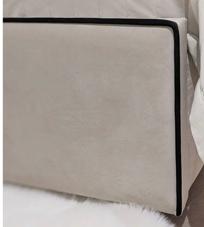 Custom Belle bed frame with high panelled headboard in beige fabric and black edge piping.